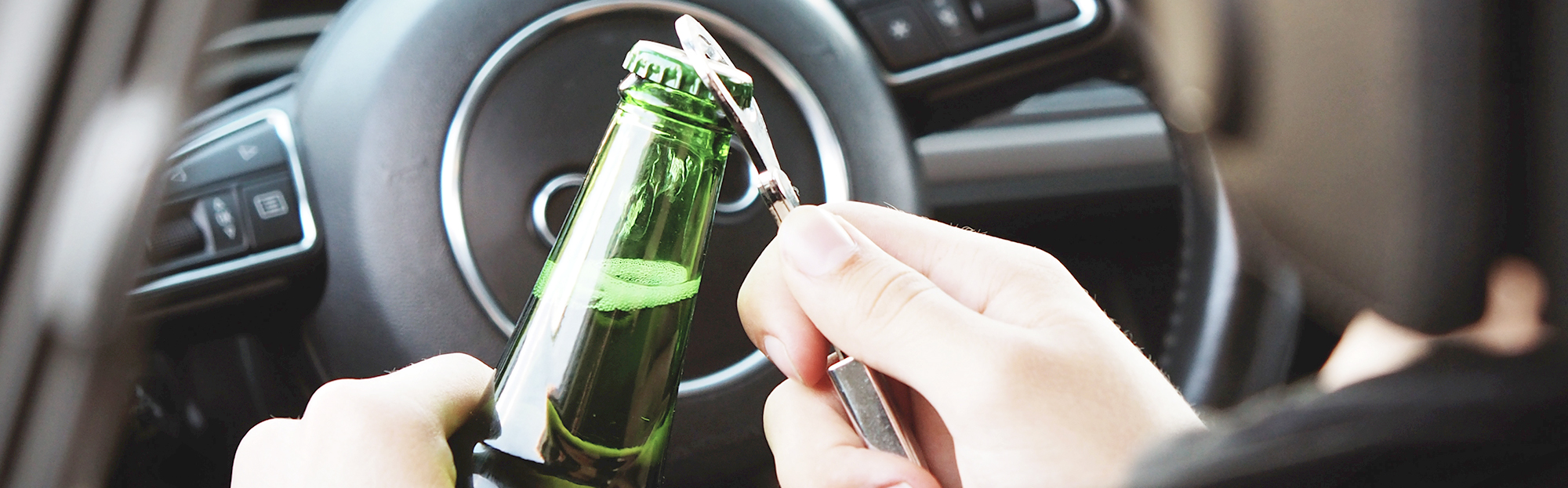 Motorist opens beer bottle inside car prior to start driving.