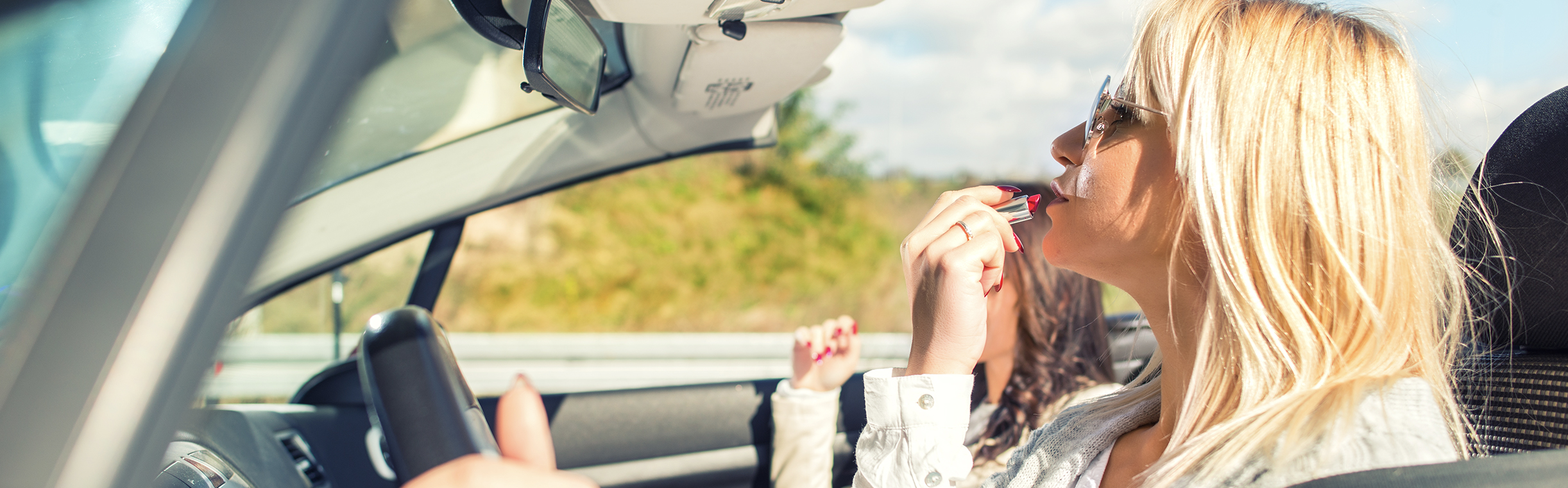 Motorist gets distracted while driving by applying lipstick.
