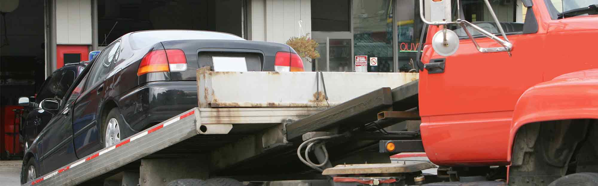 Tow truck delivers car to repair shop.