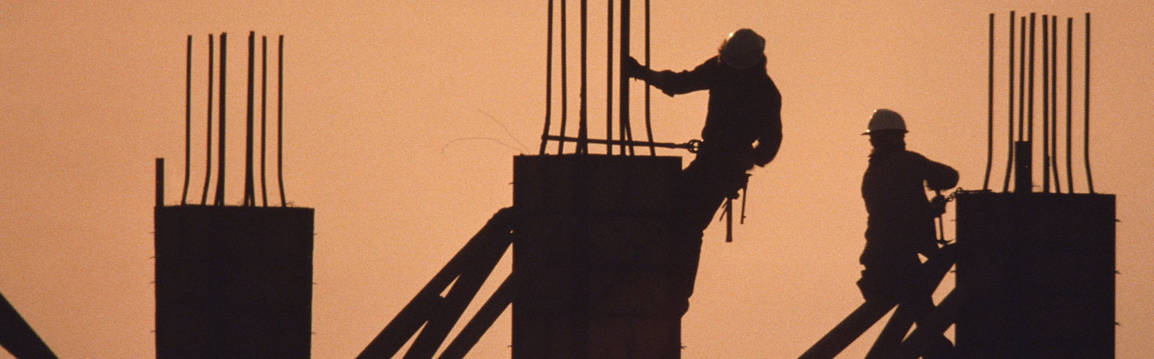 image of construction workers at dusk on a tall construction with rebar showing