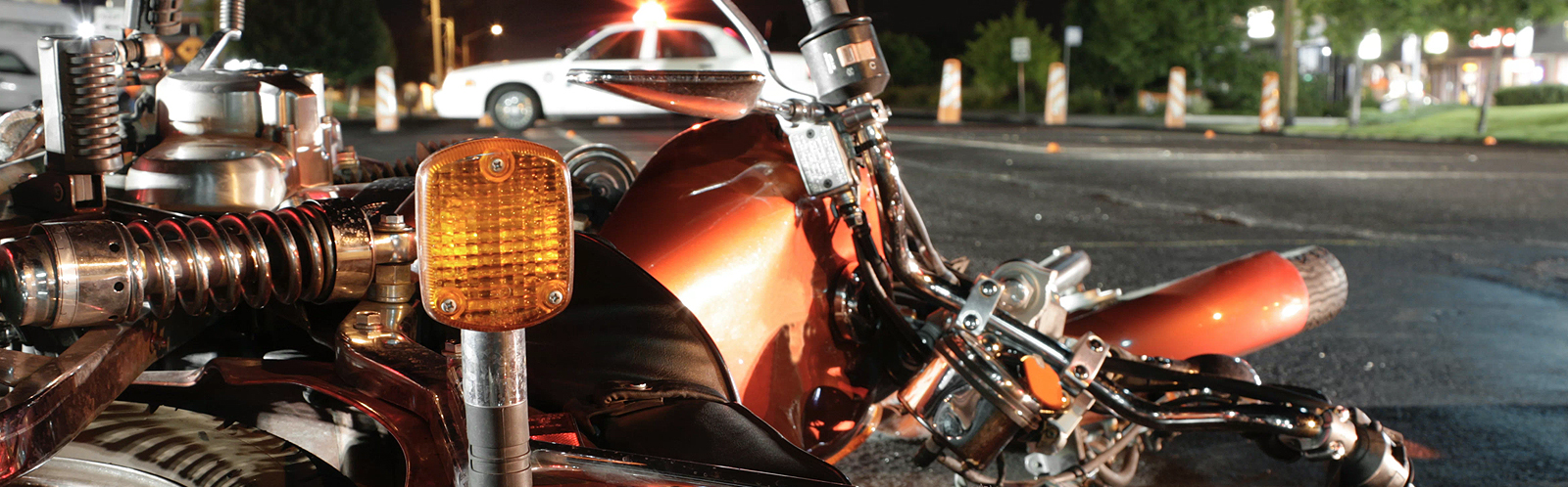 Motorcycle lies broken on the road at night after an accident.